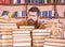 Bibliophile concept. Teacher or student with beard sits at table with books, defocused. Man on hopeful face between