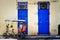 Bicitaxi driver parked up, infront of two blue doors, in the shade taking a rest.