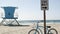 Bicycle cruiser bike by ocean beach, California coast USA. Summer cycle, lifeguard tower, road sign