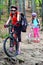 Bicycle girls with rucksack cycling in summer park.