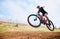 Bicycle jump, countryside and woman on a bike with speed for sports on a dirt road. Fitness, exercise and fast athlete