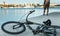 Bicycle Lies On pier Next To A Young Man Enjoys View Of Nature, Rear View