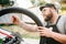 Bicycle mechanic in apron adjusts bike spokes