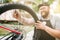 Bicycle mechanic in apron adjusts bike spokes