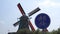 Bicycle road sign and big traditional Dutch windmill on background in Zaanse schans, Netherlands.