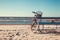 Bicycle stands near bench on beach against sea.