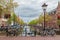 Bicycles on Amsterdam streets near canal with traditional old houses, bridge and church in the background.