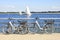 Bicycles parked on embankment, sailboats on background