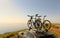 Bicycles on the roof of the car on the edge of the mountain against the backdrop of the sea and sunset