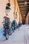 Bicycles, sculptures, benches standing in a long outdoor Pantheon corridor of University of Szeged. The University of Szeged is a