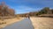 A bicyclist and walker on a paved trail in autumn