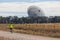 A bicyle rider approaching a large outdoor scientific radio telescope
