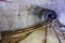Bifurcation of rusty narrow-gauge railway. Tunnel in abandoned mine. Turn the tunnel. Light from the turn