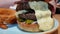 Big appetizing burger with double meat cutlet, onion rings, pickles, melted cheese, and bacon. Hamburger on plate in restaurant,