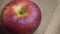 Big apple of the Gala variety on a wooden surface, 4k macro video resolution. The bitten apple rotates. A place for the text, a