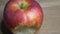 Big apple of the Gala variety on a wooden surface, 4k macro video resolution. The bitten apple rotates. A place for text, copy