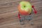 Big apple laying in shopping cart. Wooden background