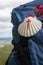 Big backpack with pilgrim shell on mountain background. Pilgrimage concept. Pilgrim on Camino de Santiago road.