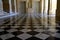 Big beautiful beige empty hallway with black and white chess tile floor in the palace of Versailles