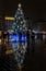 Big beautiful illuminated Christmas tree at Krakow city center, reflected on wet pavement