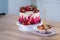 Big beautiful red velvet cake, with flowers and berries on top. Delicious sweet muffins with cream,