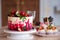 Big beautiful red velvet cake, with flowers and berries on top. Delicious sweet muffins with cream,