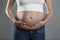 Big belly of a pregnant woman on a faithful background. Pleasant expectation. Close-up