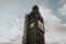 Big Ben clock with Scaffolds, during restoration works, with sun and clouds in the background, in London, England