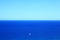 Big blue ocean with small white sailing boat, vastness