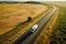 Big blue truck driving fast with a white trailer with blank space for text on a countryside road with other cars against