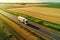 Big blue truck driving fast with a white trailer with blank space for text on a countryside road with other cars against