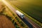 Big blue truck driving fast with a white trailer with blank space for text on a countryside road with other cars against