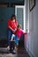 Big boots, little feet. Full length shot of a mother helping her daughter try on a pair of large rain boots at home.