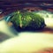 Big boulders covered by fresh green moss in foamy water of mountain river. Light blurred cold water with reflections, white