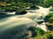 Big boulders covered by fresh green moss in foamy water of mountain river. Light blurred cold water with reflections, white