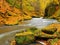 Big boulders with fallen leaves. Autumn mountain river banks. Gravel and fresh green mossy boulders on banks with colorful