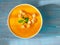 big bowl of pumpkin soup on a wooden blue background. Bright tasty dish, top view