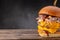 Big burger with double beef cutlet, melted cheese and vegetable salad on a wooden board