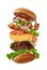 Big burger with flying ingredients isolated on white. Ham, beef cutlet, cheese, mayonnaise, ketchup, vegetables and