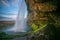 Big cave behind The Seljalandsfoss waterfall in Iceland with evening sky