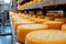 Big cheese wheels at manufacturing closeup. A cheese dairy in a warehouse with cheese
