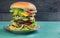 Big cheeseburger deluxe high on green wooden background