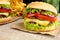 Big cheeseburgers with french fries on wooden desk