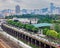 Big city street, loaded with cars, traffic jam along the road river park with green trees, urban architecture.