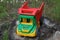 Big colored toy dump truck stands on a stump in the green grass