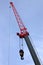 Big construction arm crane with heavy hook on clear blue sky, vertical photo