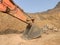 big digging bucket of backhoe or excavator beside stone pile