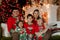 Big family of five in Christmas pyjamas sitting together on a sofa