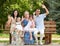 Big family sit on wooden bench in city park and waving, summer season, child, parent and grandmother, group of five people