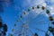 Big Ferris wheel against blue sky with clouds